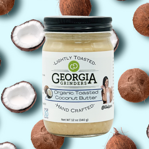 Jar of Georgia Grinders coconut butter surrounded by coconuts on a light blue background