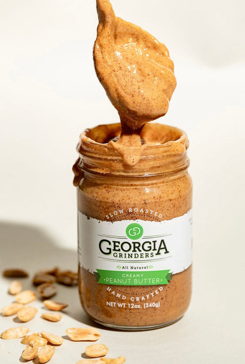 Jar of Georgia Grinders peanut butter with a spoonful of peanut butter on a light background