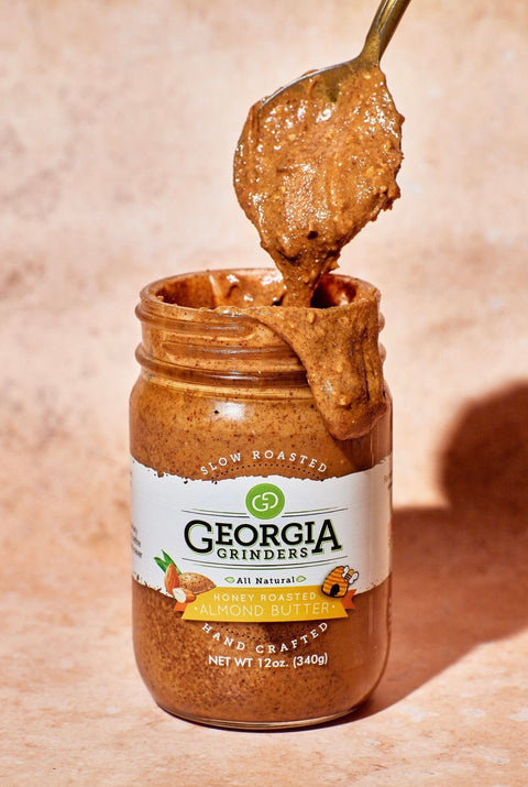 Jar of Georgia Grinders honey roasted peanut butter with a spoonful being lifted out.