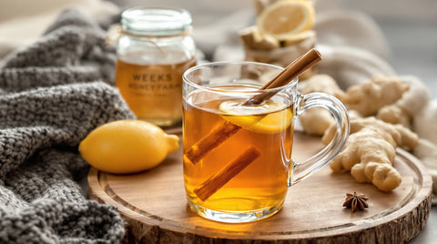 Steaming hot toddy with lemon, cinnamon stick, and Weeks Ceylon Cinnamon honey on a cozy knit blanket