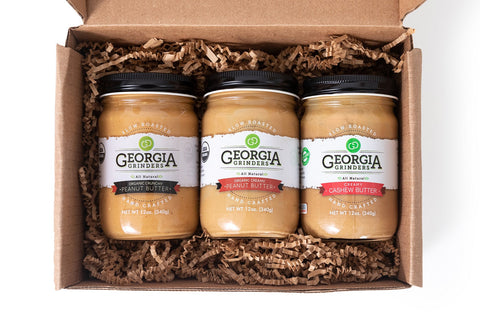 Three jars of Georgia Grinders peanut and cashew butter in a cardboard box.