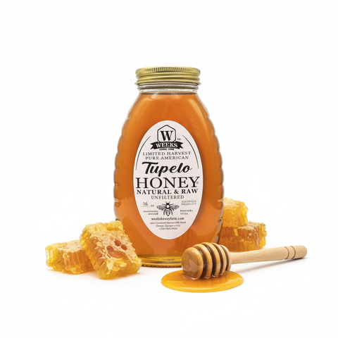 Bottle of Weeks Tupelo Honey with honeycomb and dipper on a white background