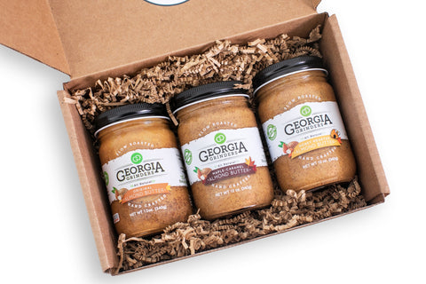 Three jars of Georgia Kitchen spread in a cardboard box on a white background