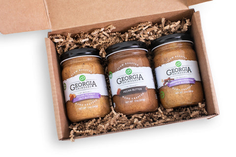 Three jars of Georgia Gingers peanut butter in a cardboard box on a white background
