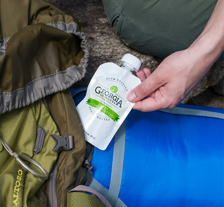 Hand holding a Georgia Pacific cleaning product next to a green backpack on a blue surface